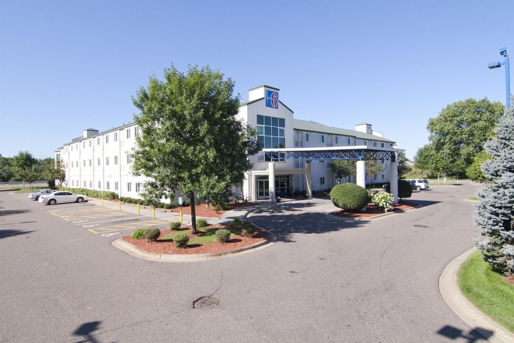 Un hotel con entrada techada, aparcamiento y un edificio con el número '6'.