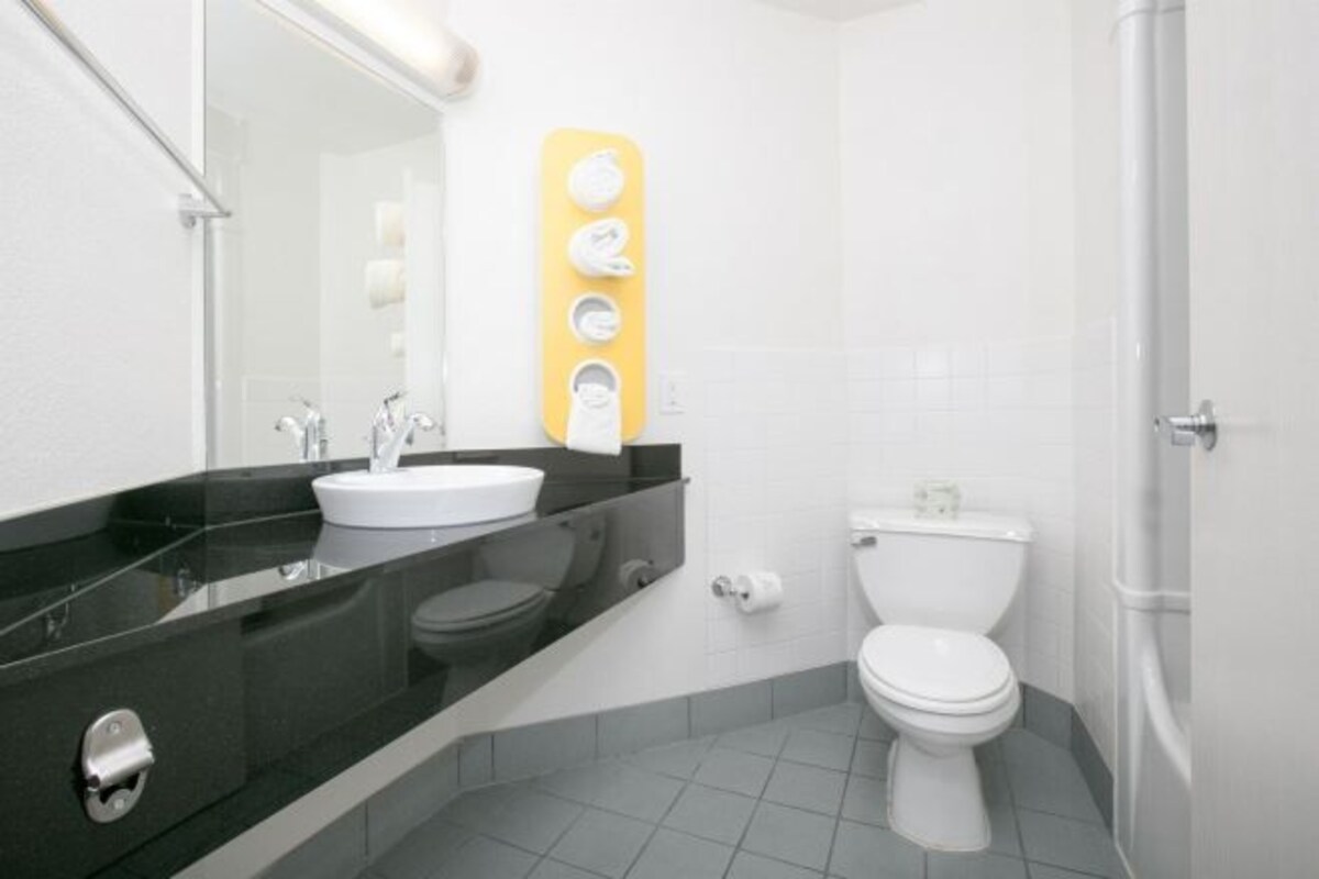 Un baño moderno con encimera negra, lavabo blanco y retrete.