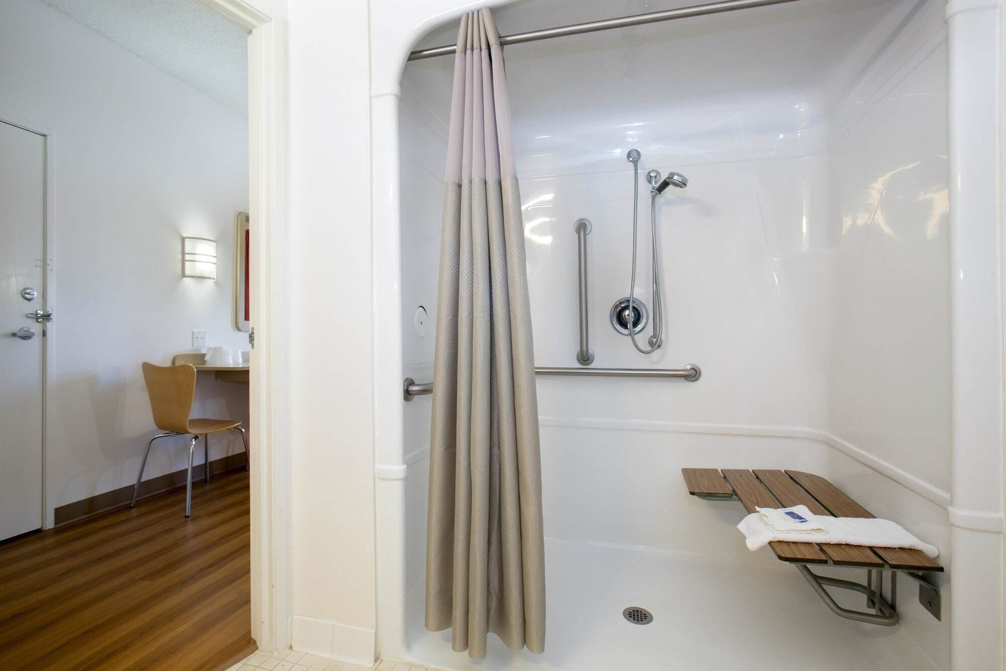 A shower with a curtain, a bench, and a towel rack.