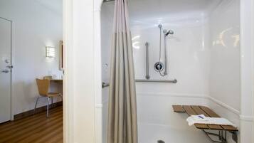A shower with a curtain, a bench, and a towel rack.