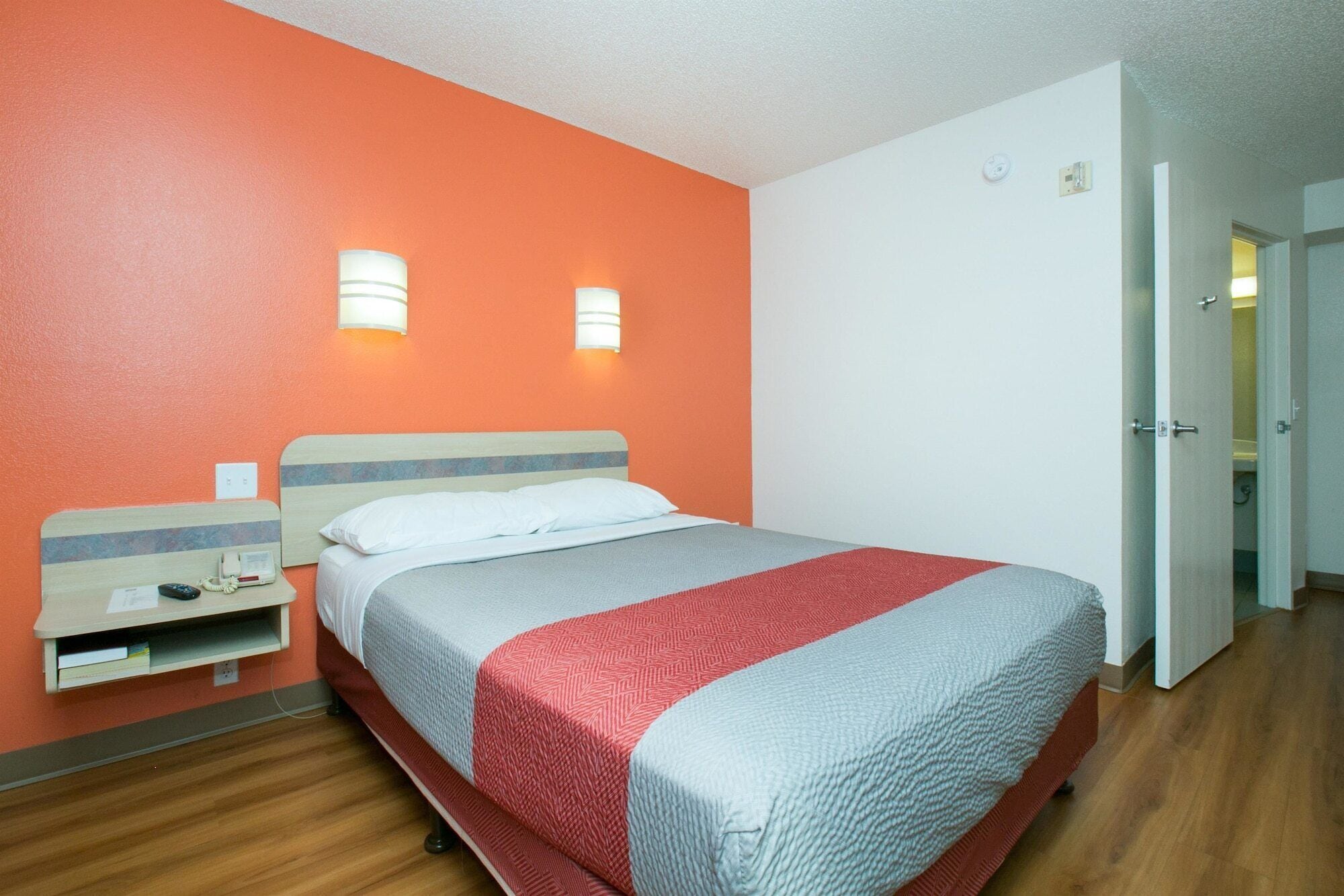 A hotel room with a bed, bedside tables, and a door leading to a bathroom.
