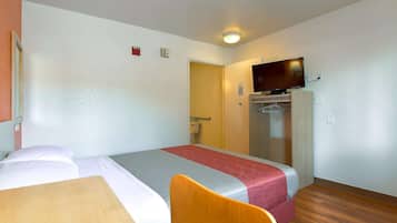 Habitación de hotel con cama, una mesa de madera, una silla, televisión y armario.