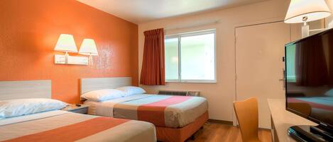 Habitación de hotel con dos camas, un escritorio con televisor y una ventana con cortinas.