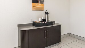 A hotel reception area with a dark brown cabinet, a coffee machine, and a framed sign above it. - Motel 6 Fort Worth, TX - North (Fort Worth)