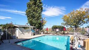 A swimming pool with a tiled edge, surrounded by lounge chairs and a fence. - Motel 6 Prescott, AZ (Prescott)