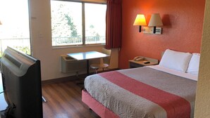 A hotel room with a bed, a desk, a chair, a heater, a telephone, and a window with curtains. - Motel 6 Prescott, AZ (Prescott)