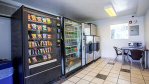 A vending area with snack and drink machines, a microwave, and a small table with chairs. - Motel 6 Prescott, AZ (Prescott)