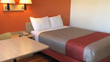 A hotel room with a bed, two bedside lamps, a desk, and a telephone.