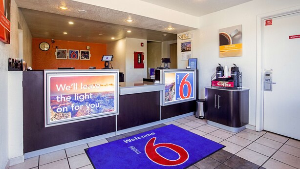 A hotel reception area with a clock, a welcome mat, and a coffee station. - Motel 6 Prescott, AZ (Prescott)