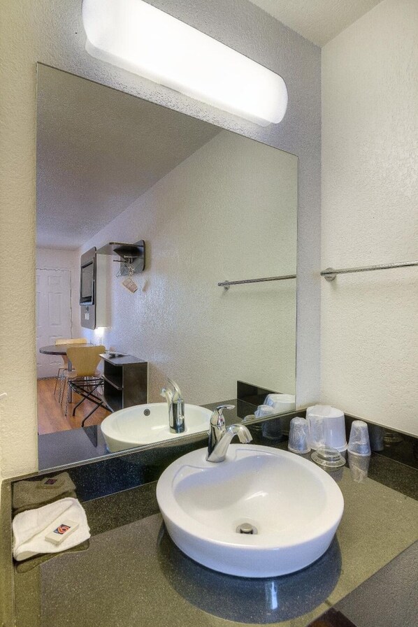 Une salle de bain d’hôtel avec un grand miroir, deux lavabos et un porte-serviettes.
