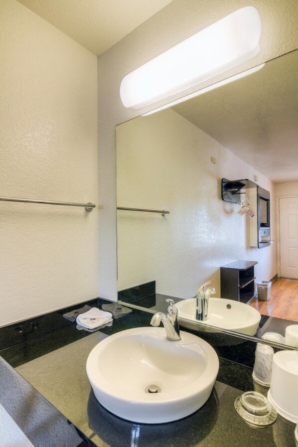 A bathroom with a white sink, a mirror, and a towel rack. - Motel 6 Simi Valley, CA (Simi Valley)