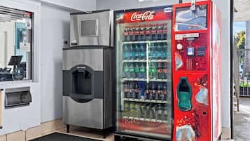 A vending machine with a Coca-Cola logo, a water dispenser, and a payment terminal.