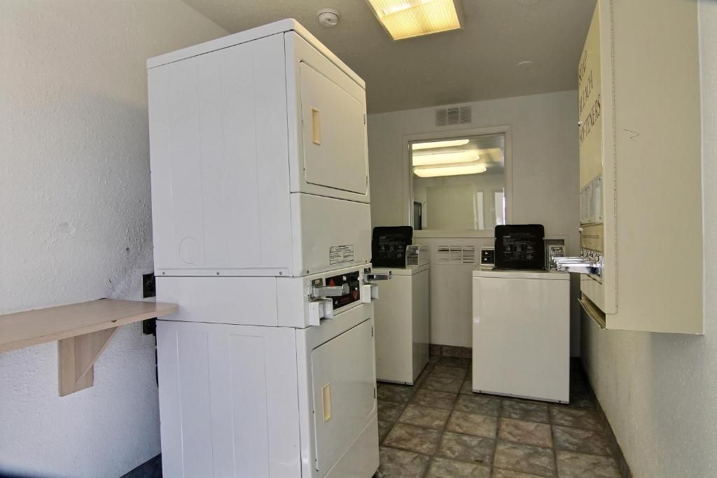 A compact kitchen with a refrigerator, washing machine, and coffee maker.