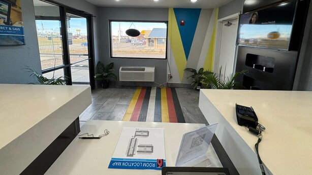 An office reception area with a desk, a computer, and a window with a view of the outside. - Motel 6 Bismarck, ND (Bismarck)