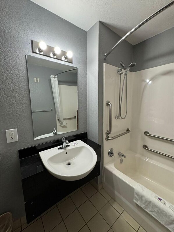 A modern bathroom with a white sink, mirror, and shower. - Motel 6 Bismarck, ND (Bismarck)