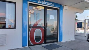 A building entrance with a 'welcome' sign, a large glass door, and a 'Registered Guest Only' sign. - Motel 6 Bismarck, ND (Bismarck)