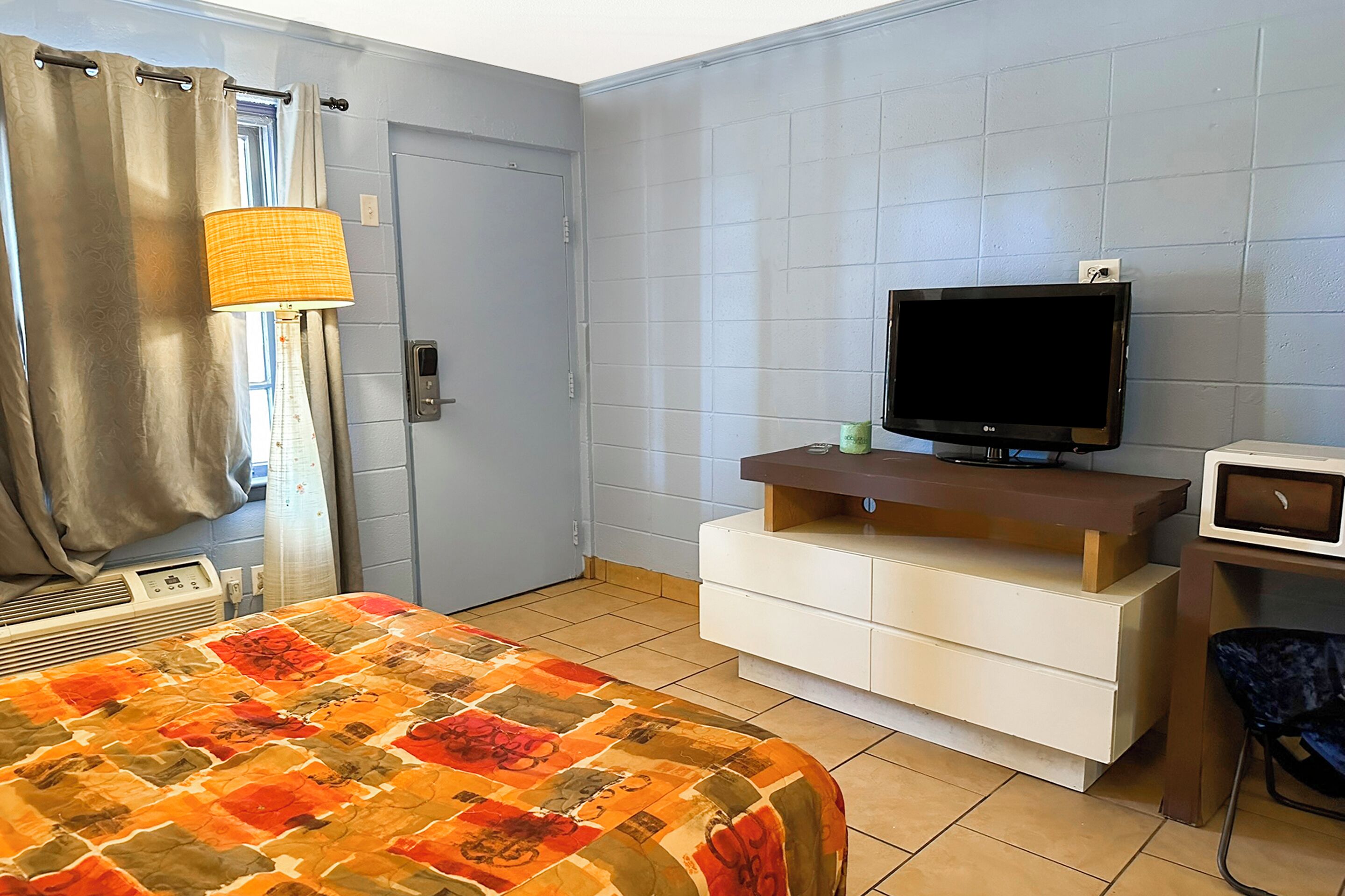 A hotel room with a bed, a television, a desk, and a chair.