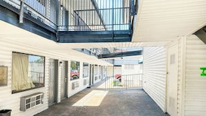 A corridor with a covered walkway, windows, and a trash bin. - Luxury Inn by OYO Albany (Albany)
