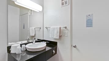 A bathroom with a white sink, black countertop, and a mirror. There are two white towels hanging on towel bars.