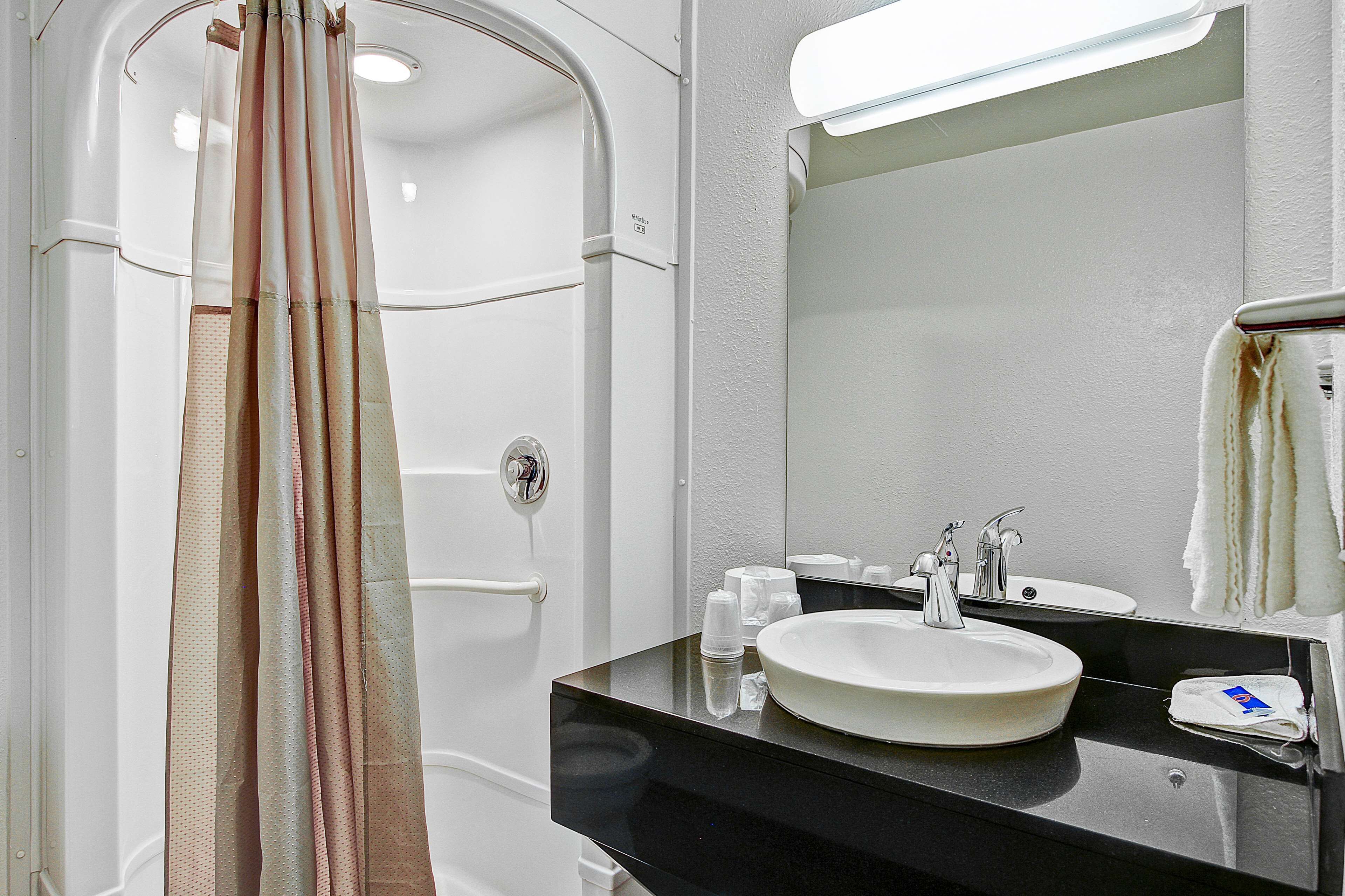 A bathroom with a white sink, a mirror, and a shower curtain.
