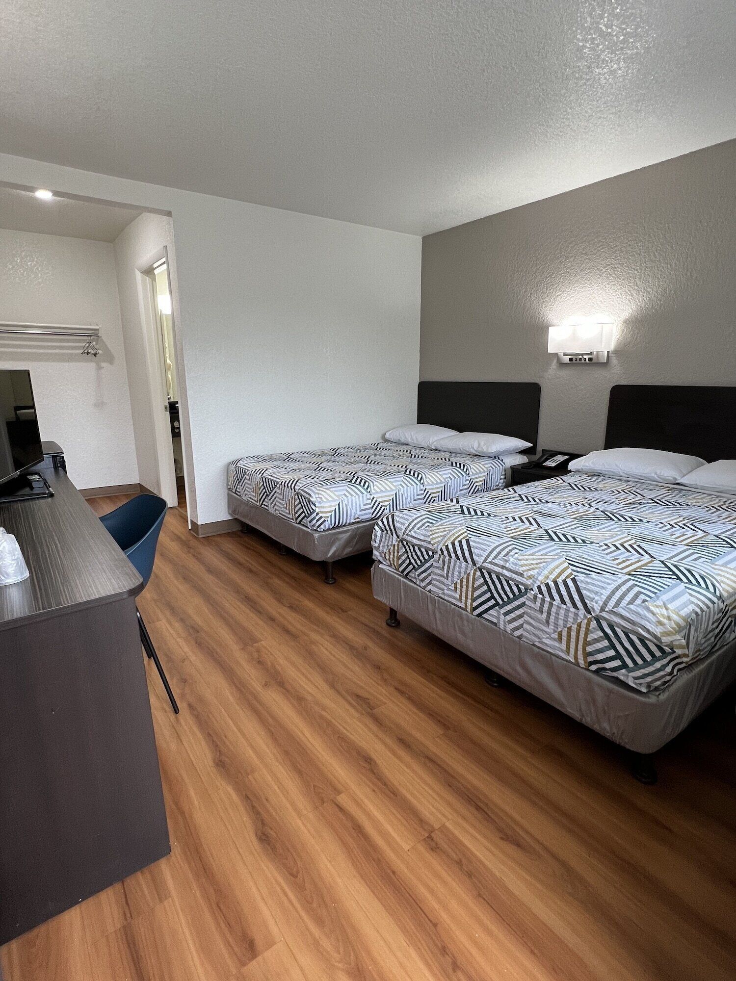 Een hotelkamer met twee bedden, een bureau en een stoel.