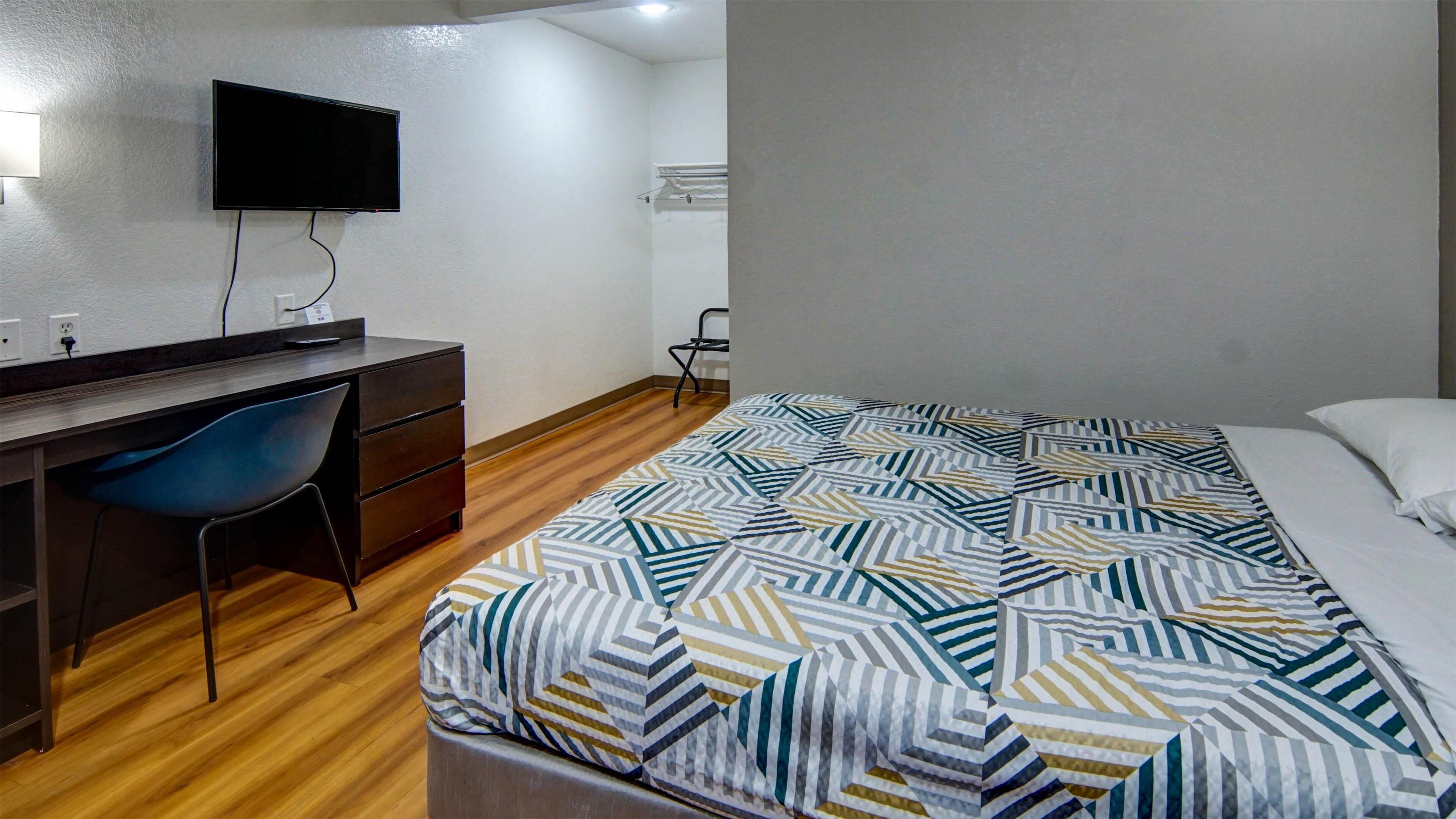 A bedroom with a bed, a desk, and a chair.