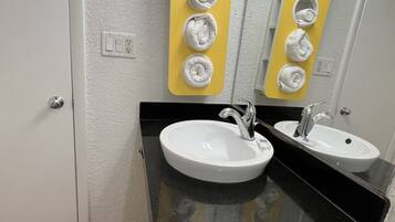 A bathroom with two sinks, a mirror, and a towel rack with five towels.