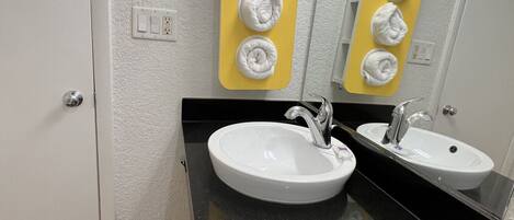 A bathroom with two sinks, a mirror, and a towel rack with five towels.