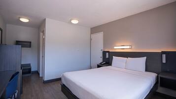 Een hotelkamer met een bed, nachtkastjes, een bureau, een stoel en een kledingkast.