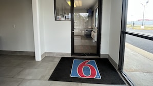 Entrada de hotel com um tapete preto exibindo o número '6' em tamanho grande.