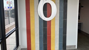 Un couloir avec un grand chiffre « 6 » blanc sur un mur recouvert de carreaux colorés.