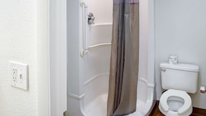 Une salle de bain équipée d’une douche, de toilettes et d’une prise électrique murale.