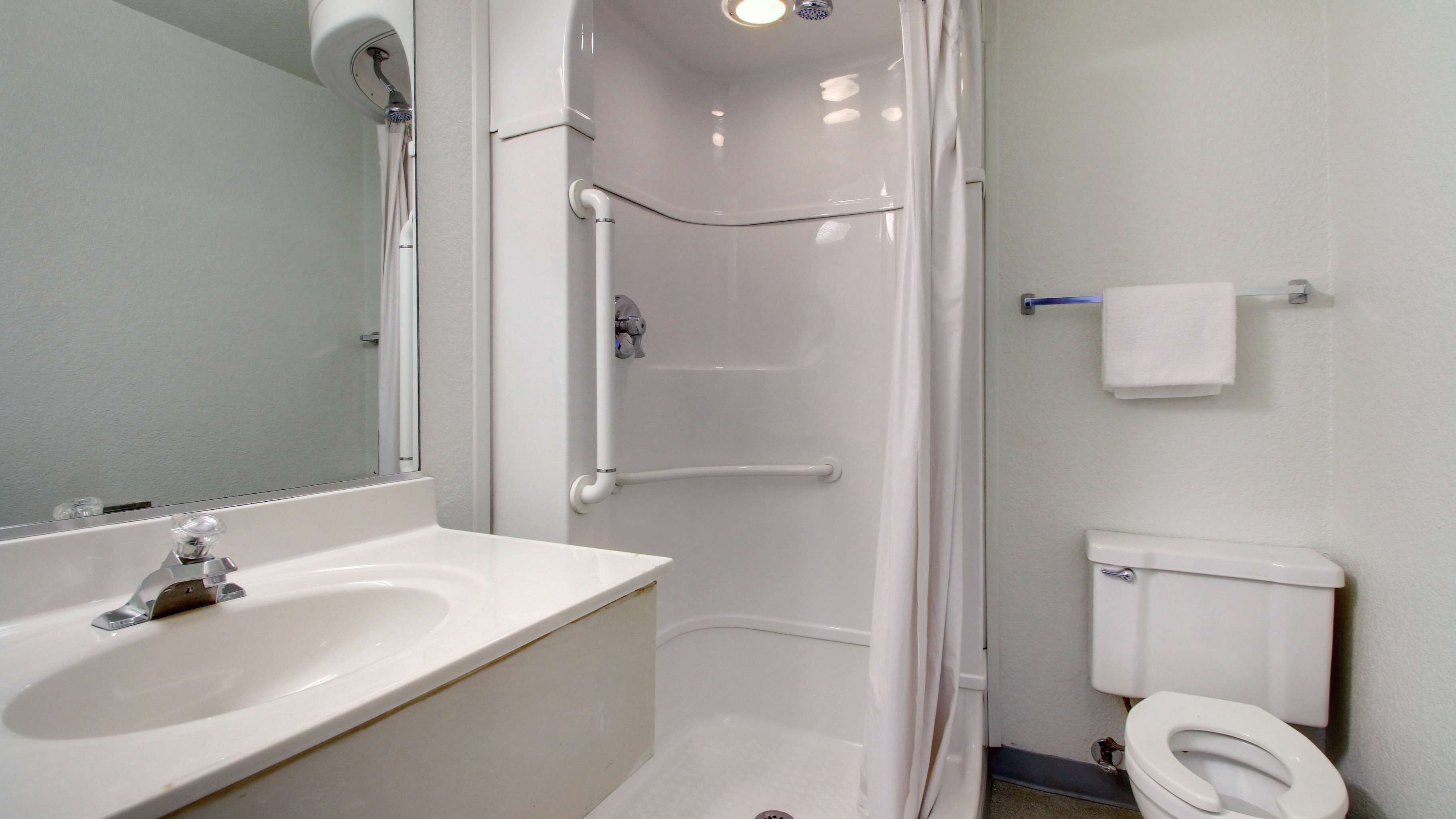 Une salle de bain avec un lavabo blanc, des toilettes et une cabine de douche.