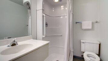 Une salle de bain avec un lavabo blanc, des toilettes et une cabine de douche.