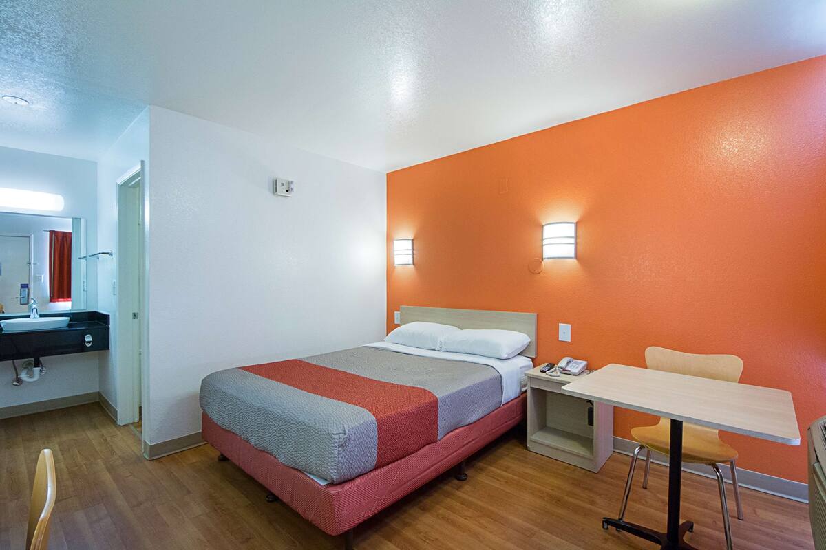 A hotel room with a bed, a desk, and a chair.