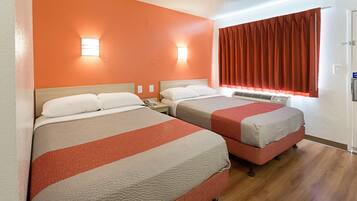 A hotel room with two beds, a window with curtains, and wall-mounted lights.