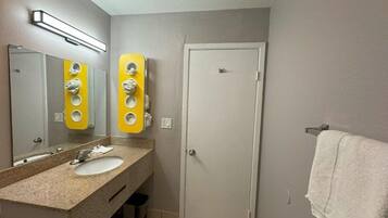 Un baño con lavamanos, espejo, perchero y puerta.