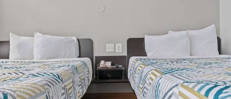 A hotel room with two beds, a nightstand, and a wall-mounted phone.