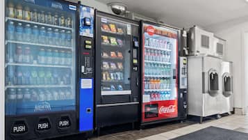 Una hilera de máquinas expendedoras con diversas bebidas y aperitivos, incluyendo agua Aquafina, Coca-Cola y otras marcas.