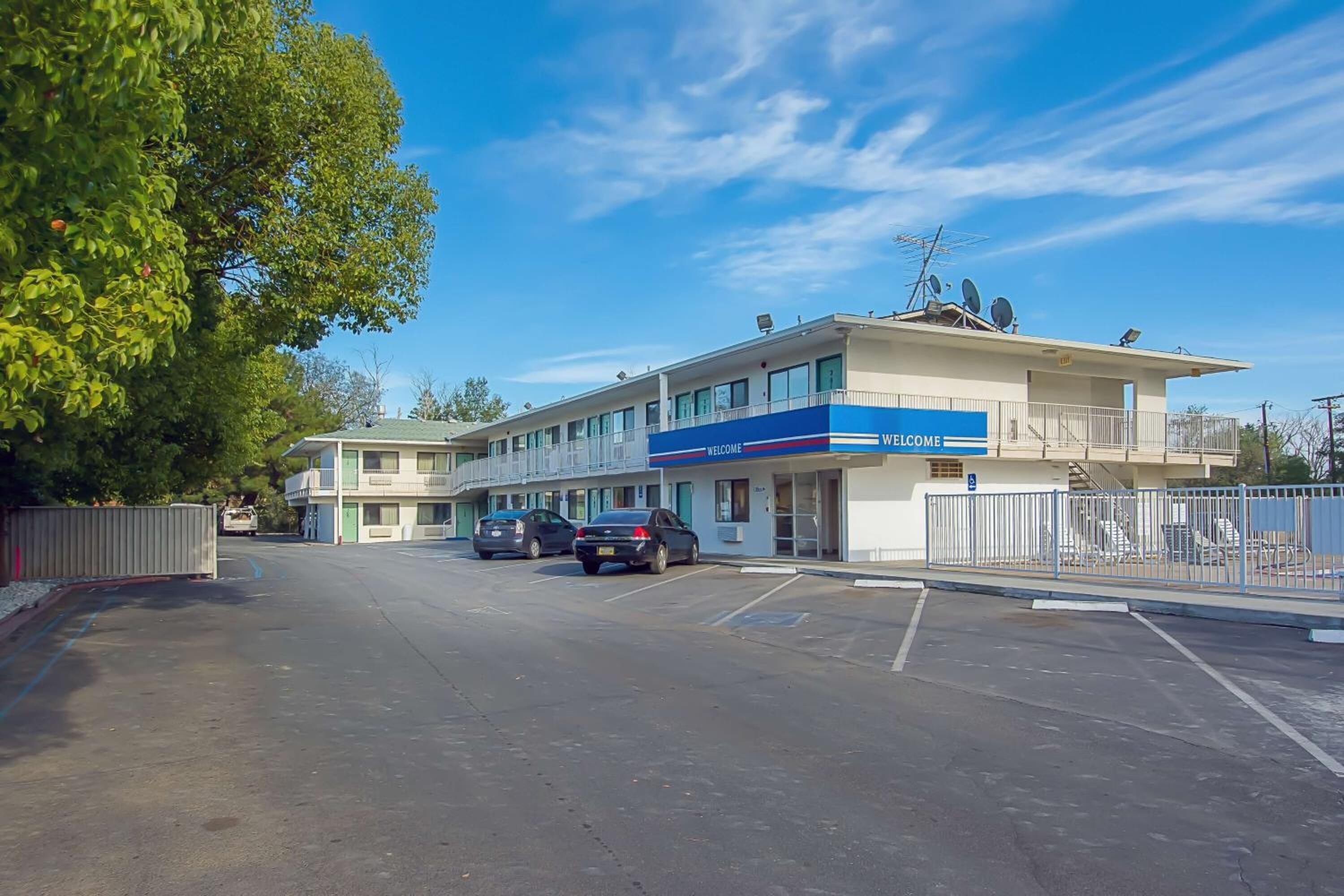 Un hôtel avec une enseigne « BIENVENUE », un parking et un bâtiment doté de balcons.