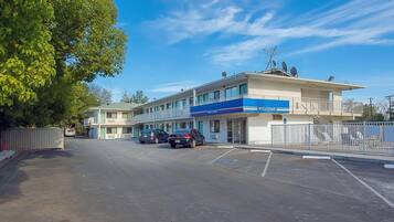 Un hôtel avec une enseigne « BIENVENUE », un parking et un bâtiment doté de balcons.
