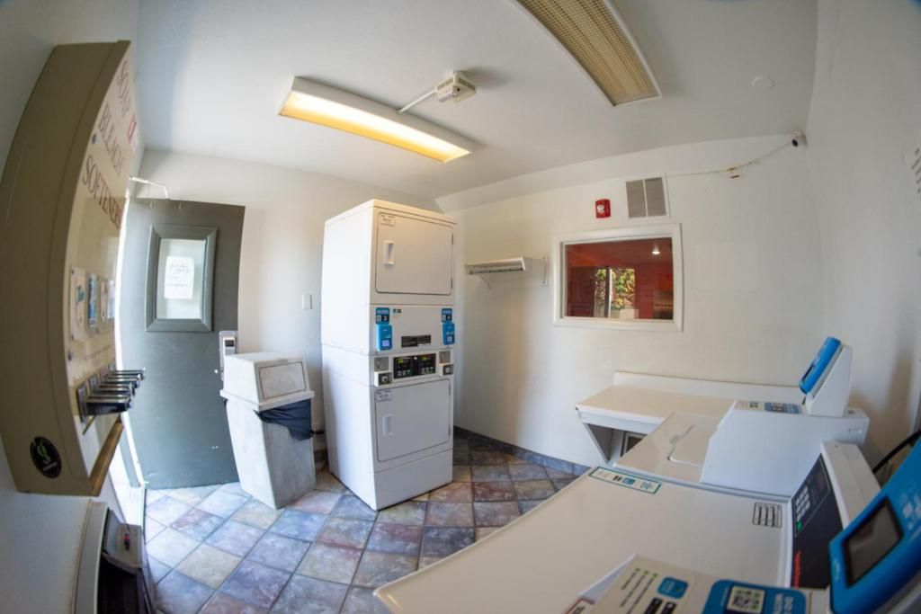 Un cuarto de lavandería con lavadora, secadora y una pequeña mesa con una computadora.