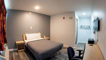 A compact hotel room with a bed, bedside tables, a desk, and a chair.