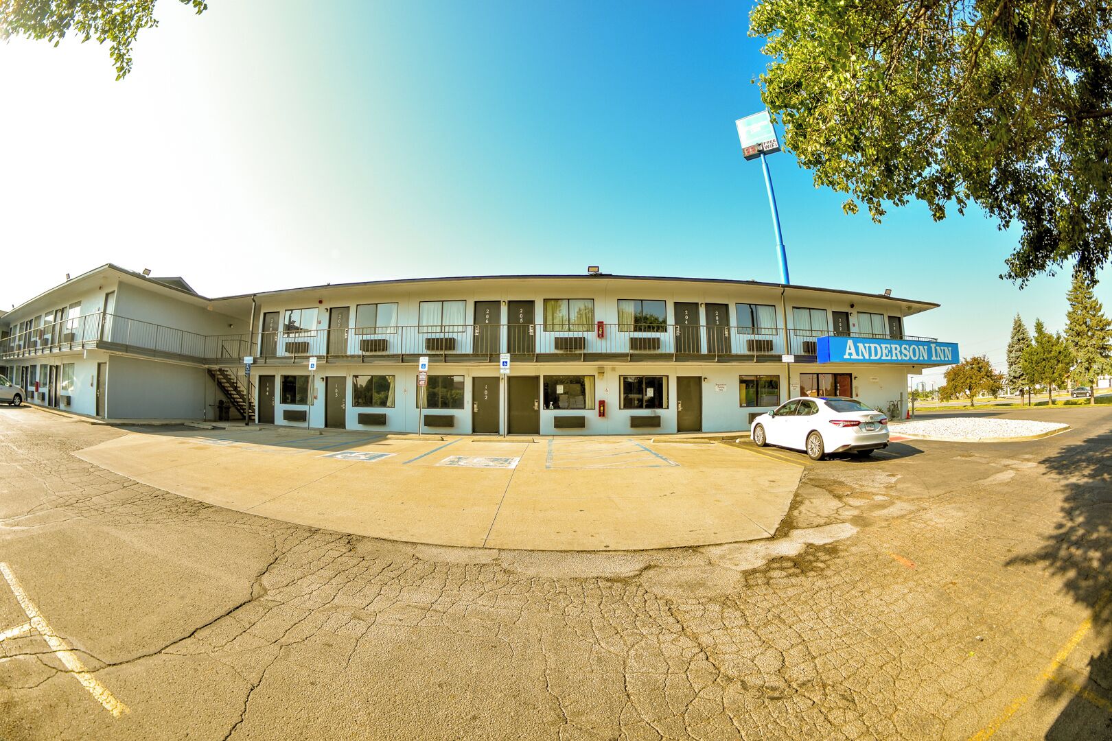 A motel with a parking lot, a car parked in front, and a sign for the Anderson Inn.