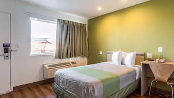 A hotel room with a bed, a desk, and a chair.
