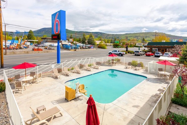 Un motel con piscina, asientos al aire libre y vistas del entorno.