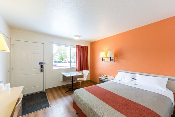 A hotel room with a bed, desk, chair, and a window with curtains. - Motel 6 Klamath Falls, OR (Klamath Falls)