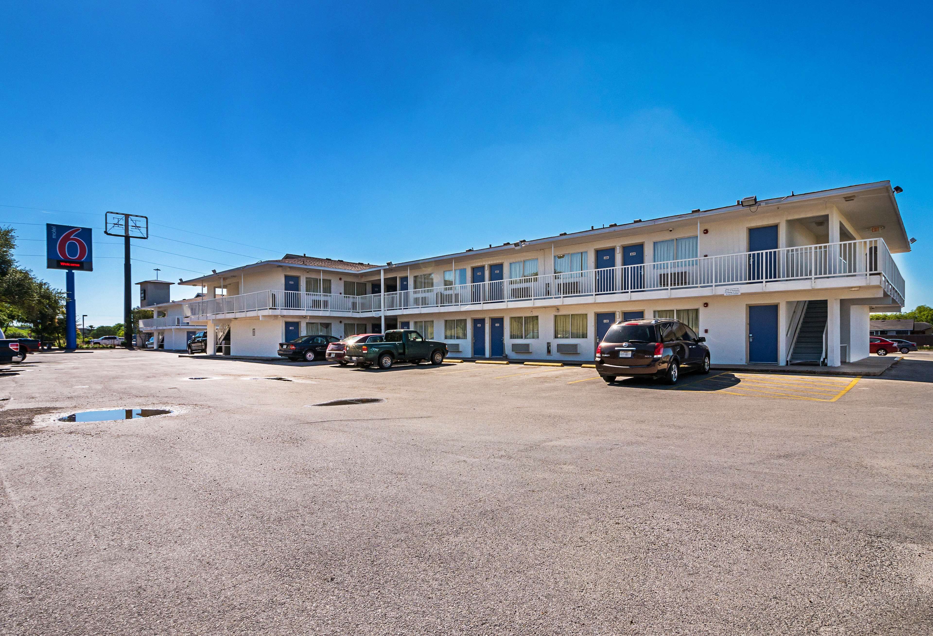 Un motel composé d’un bâtiment à deux étages, doté de nombreux balcons, et d’un parking où sont stationnés plusieurs véhicules.