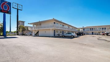 Un motel con un grande cartello che riporta '6 Welcome' e un parcheggio con diverse auto.
