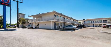 A motel with a large sign reading "6 Welcome" and a parking lot with several cars.